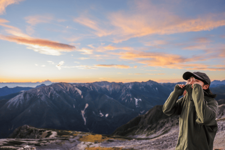 絶景をバックにレインウェアを着る女性