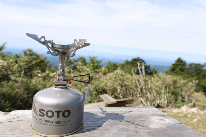 SOTOウインドマスターに4本ゴトクを装着しガス缶に取り付けた状態と山の風景